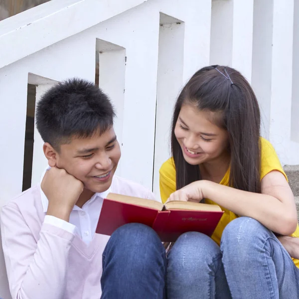 öğrenciler kitap kullanarak merdivenlerde oturan arkadaşlar