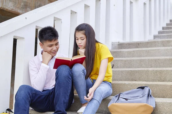 Studenti amici seduti sulle scale utilizzando libro — Foto Stock