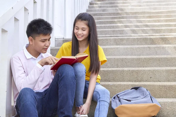 öğrenciler kitap kullanarak merdivenlerde oturan arkadaşlar