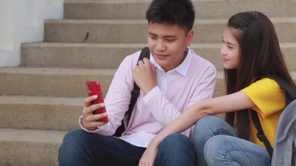 スマートフォンで微笑んでいる女の子と少年十代の若者たちは自分撮りを作る — ストック動画
