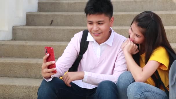 女孩和男孩青少年玩微笑与智能手机坐在制作自拍 — 图库视频影像