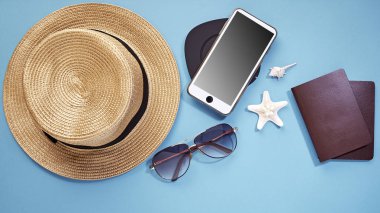 şapka akıllı telefon ve güneş gözlüğü mavi arka plan