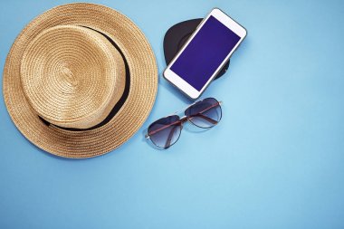 şapka akıllı telefon ve güneş gözlüğü mavi arka plan