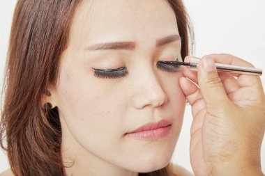 Makyaj sanatçısı müşteri kirpik yapıştırıyor