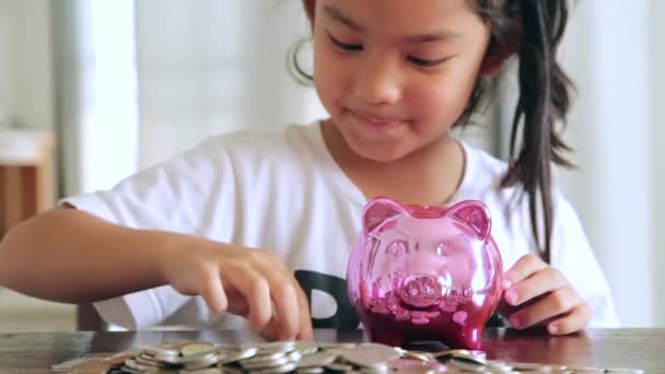 Cute Girl Putting Coins Piggy Bank Home — Stock Video