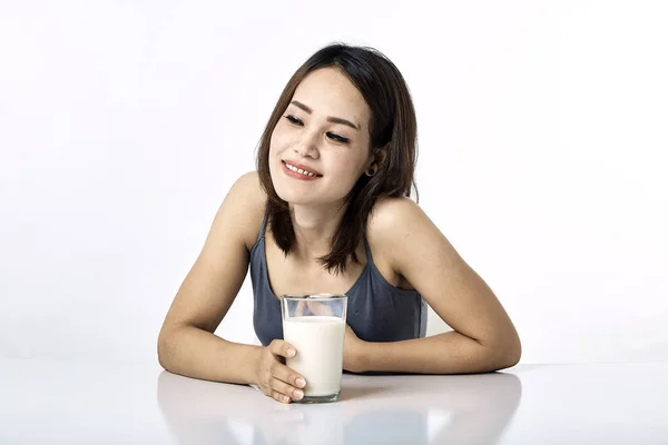 Молодая женщина пьет молоко на столе — стоковое фото