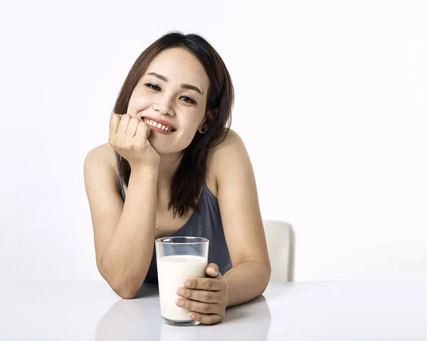 Ung kvinna dricker mjölk på bordet — Stockfoto