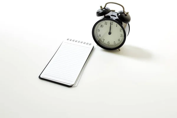 Despertador com notebook branco em branco — Fotografia de Stock