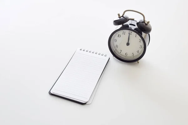 Despertador com notebook branco em branco — Fotografia de Stock