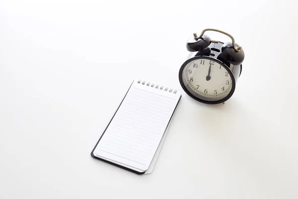 Despertador com notebook branco em branco — Fotografia de Stock