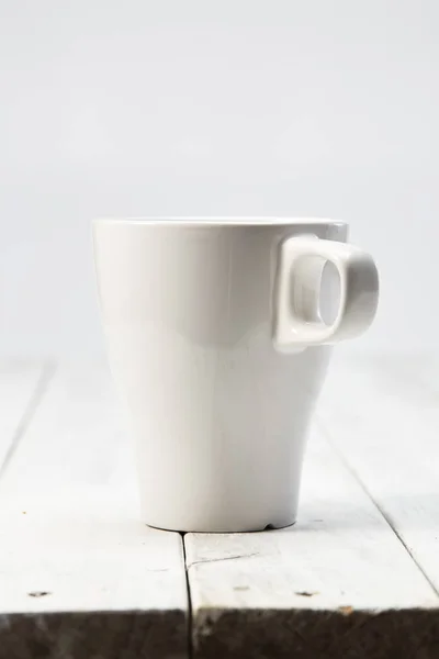 Белая пустая чашка на деревянном столе — стоковое фото