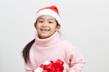 Kazak ve noel baba şapkalı bir hediye kutusu tutan kız