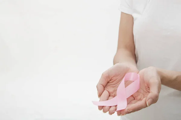 Manos femeninas sosteniendo cinta rosa . — Foto de Stock