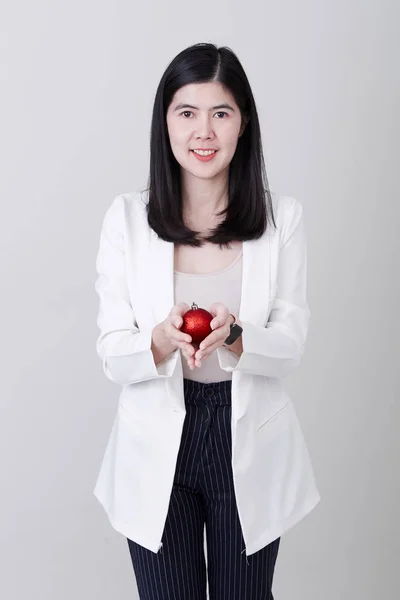 Mujer asiática mano sosteniendo una bola roja de Navidad — Foto de Stock