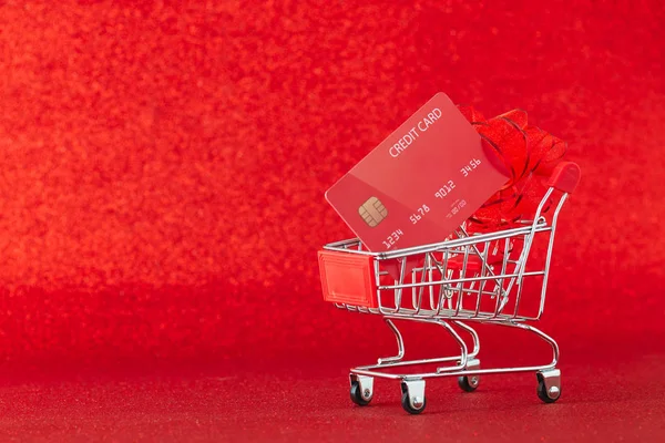 Mini wózek supermarketowy z kartą kredytową na czerwonym tle — Zdjęcie stockowe