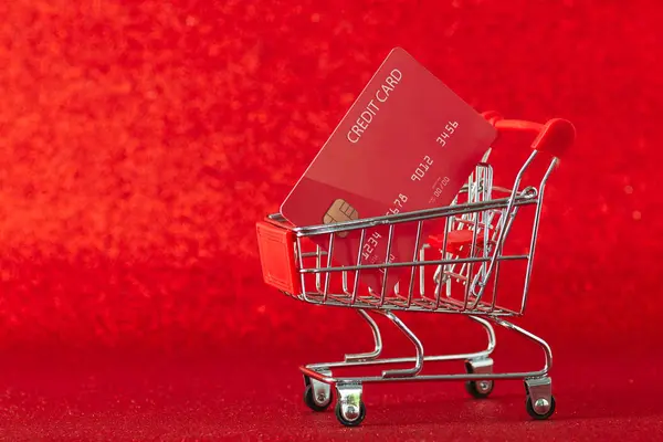 Mini supermarket vozík s kreditní kartou na červeném pozadí — Stock fotografie