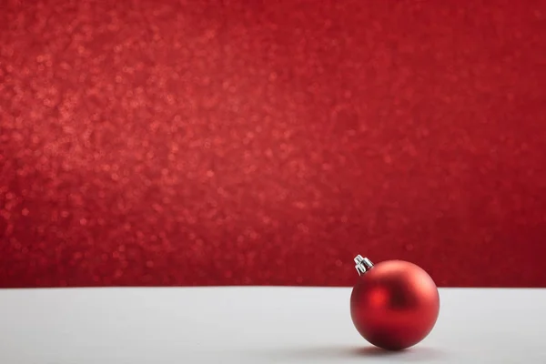 Vánoční míč na bílém stole červená zeď — Stock fotografie
