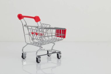 Minyatür alışveriş arabası ve beyaz sepet.