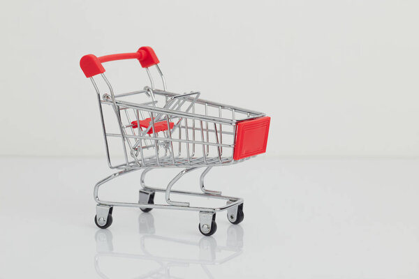 Miniature shopping cart and basket on white