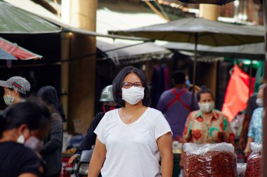 Korona virüsünden korunmak için kalabalık pazar caddelerindeki virüslere karşı korunmak için maskeli Asyalı kadınlarla dolu.