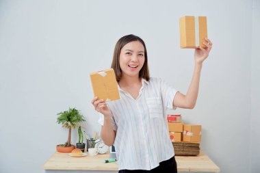 Asyalı kadın paket siparişi tutuyor, ev ofisinde çalışıyor. Çevrimiçi pazarlama dağıtımı, başlangıç KOBİ girişimcisi veya serbest girişimci kavramı