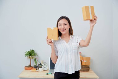 Asyalı kadın paket siparişi tutuyor, ev ofisinde çalışıyor. Çevrimiçi pazarlama dağıtımı, başlangıç KOBİ girişimcisi veya serbest girişimci kavramı