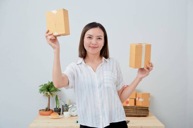 Asyalı kadın paket siparişi tutuyor, ev ofisinde çalışıyor. Çevrimiçi pazarlama dağıtımı, başlangıç KOBİ girişimcisi veya serbest girişimci kavramı