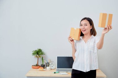 Asyalı kadın paket siparişi tutuyor, ev ofisinde çalışıyor. Çevrimiçi pazarlama dağıtımı, başlangıç KOBİ girişimcisi veya serbest girişimci kavramı