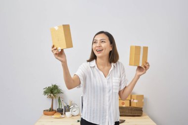 Asyalı kadın paket siparişi tutuyor, ev ofisinde çalışıyor. Çevrimiçi pazarlama dağıtımı, başlangıç KOBİ girişimcisi veya serbest girişimci kavramı