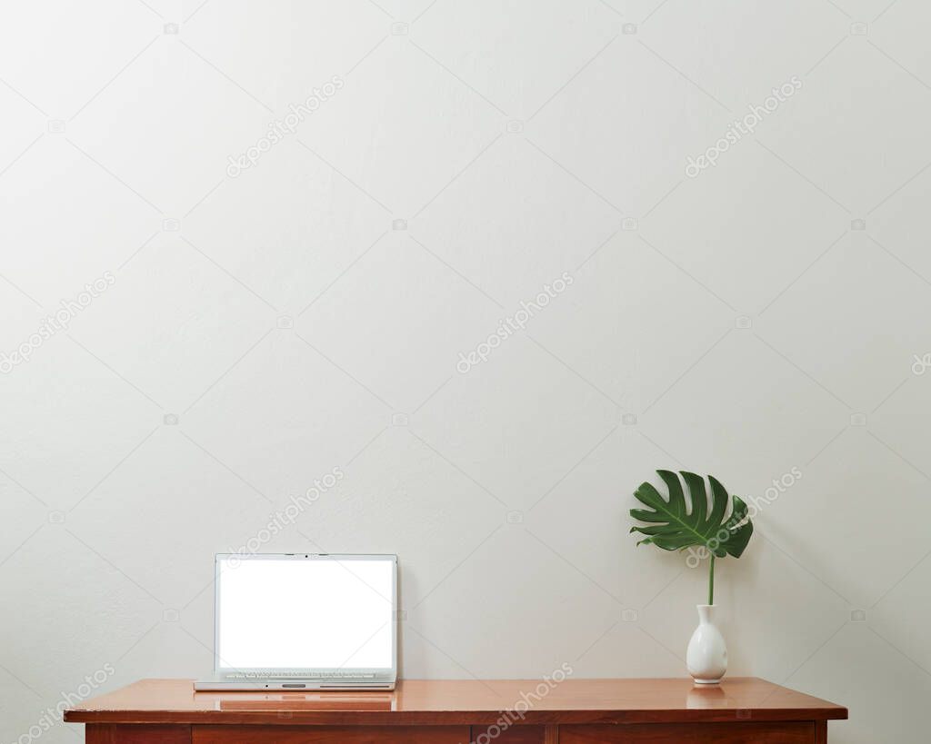 Modern computer, laptop with blank screen with Monstera leaf in vase on table and wall backgrounds, workplace , mockup concept, business workspace desk