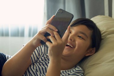 Küçük kız evdeki koltukta cep telefonu kullanmaktan hoşlanıyor..