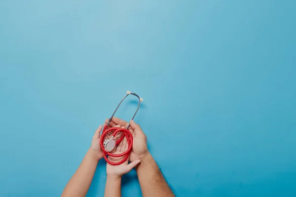 Dospělé Dětské Ruce Drží Červený Stetoskop Modrém Pozadí Kopírovacím Prostorem — Stock fotografie