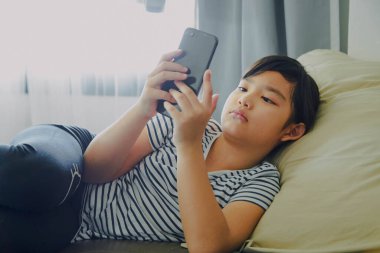 Küçük kız evde akıllı telefon kullanarak eğleniyor.