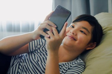 Küçük kız evde akıllı telefon kullanarak eğleniyor.