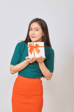 Noel 'de gülümseyen Asyalı genç bir kadın hediye kutusunu elinde tutuyor.