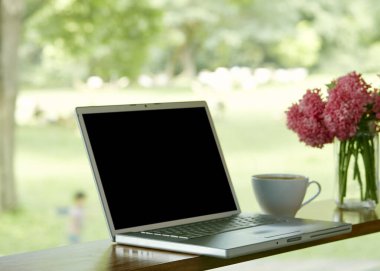 Evde boş ekran ve kahve fincanının olduğu dizüstü bilgisayarın görüntüsü.