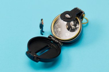 Minyatür işadamı ve pusula parlak mavi sırtüstü