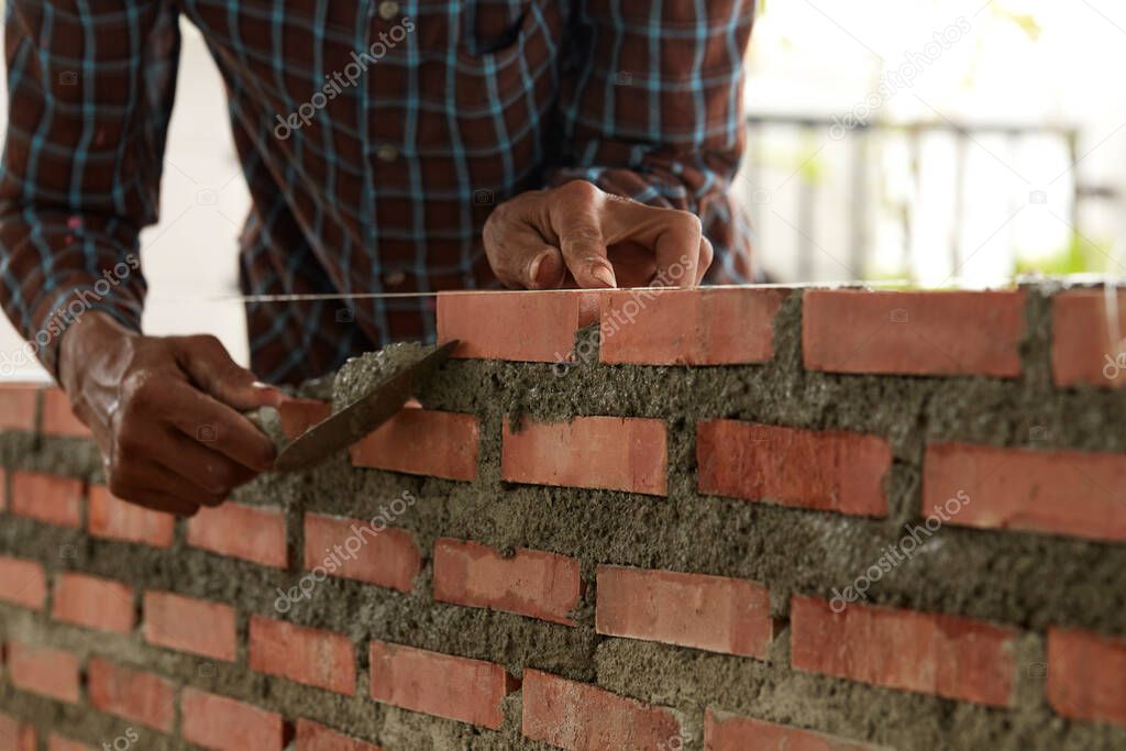 Bricklayer at work. Close up of industrial bricklayer installing bricks on construction site