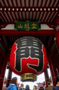 Tokyo, Japonya - 22 Eylül 2018: Tokyo 'nun Asakusa bölgesindeki tarihi Senso-ji tapınağına gelen ziyaretçiler Kaminarimon Thunder Kapısı' ndan Japonya 'nın Nakamise-dori sokak pazarına kadar uzanan dev simgesel boğaz kağıdı fenerinin altından geçiyorlar..