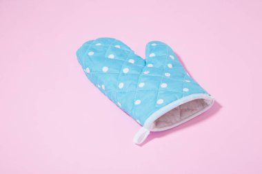 İzole edilmiş pembe arka planda mavi noktalı mutfak eldiveni