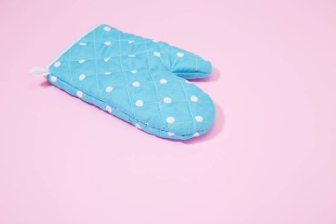 İzole edilmiş pembe arka planda mavi noktalı mutfak eldiveni