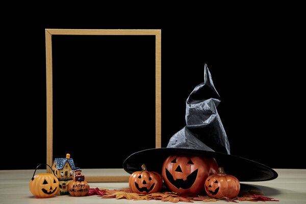 Frame and Jack O Lantern Halloween festival decoration pumpkin with witches hat on wooden table with dark background copy space for text