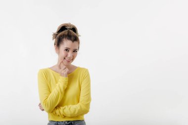 Güzel, genç, mutlu Asyalı kadınların portresi. Mutlu ve şaşırmış. Sarı kazak giyiyor.