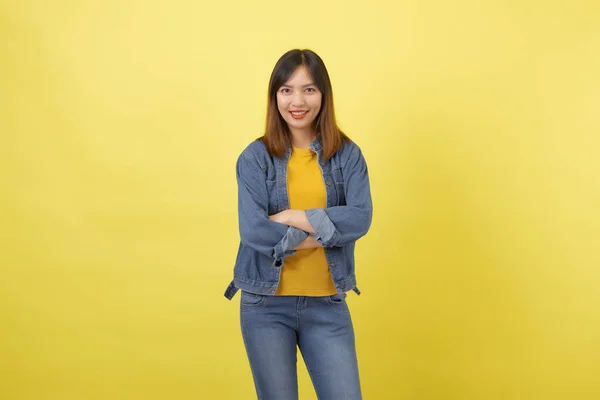 黄色を基調としたスタジオで 若くてキュートでアスレチックなタイ系アジア人の少女の肖像画 黄色のTシャツのジーンズジャケットとシンプルなジーンズを身に着けている交差腕を持つ女性 — ストック写真