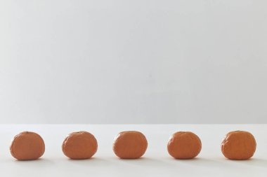 Beyaz masa arkasında turuncu meyveler izole edilmiş