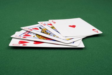 Kraliyet floşu yeşil bir keçede el ele poker oynuyor. 