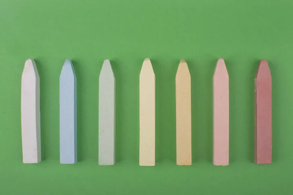 chalks in a variety of colors on green background