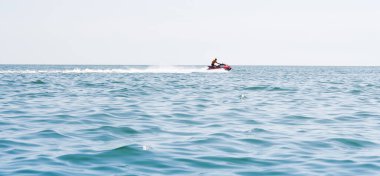 Genç bir adam jet ski ile denizde geziyor.