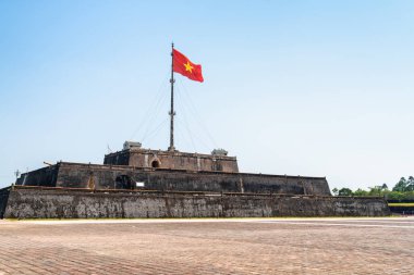 Bir kare ve Vietnam (kırmızı bayrak altın bir yıldız ile) bir kule mavi gökyüzü arka plan Hue, Vietnam için üzerinde kalenin içinde çırpınan bayrağı güzel manzarasına. Kalenin içinde İmparatorluk kentidir.