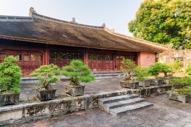 Şaşırtıcı kırmızı Tu Duc kraliyet mezarı Hue, Vietnam için bina. Binanın yanında büyüyen yeşil Bonsai Ağaçlar. Renk tonu Asya'nın popüler bir turistik yer.